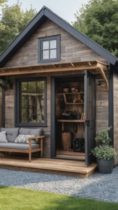 a small wooden shed with a couch and potted plants in the front yard area