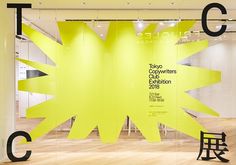 an exhibit with yellow and black letters on the wall, in front of a wooden floor