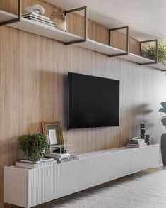 a flat screen tv sitting on top of a white entertainment center next to a potted plant