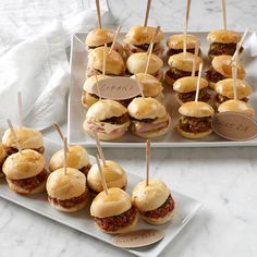 mini sandwiches are arranged on small plates with toothpicks