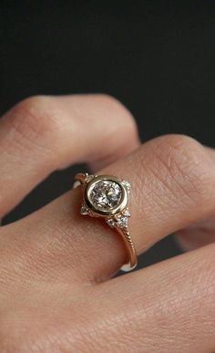 a woman's hand with a diamond ring on top of her finger and an engagement band