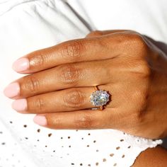 a woman's hand with a diamond ring on her left hand and white top