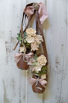 a pair of brown boots with flowers and pearls hanging on a white wooden door handle