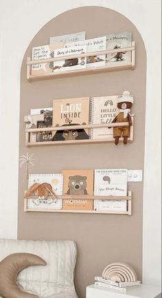 three wooden shelves with books on them in a living room next to a white chair