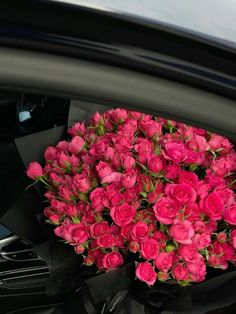 a bunch of pink roses sitting on top of a car