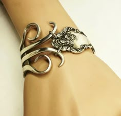 a woman's arm wearing a silver bracelet with scissors and a skull on it