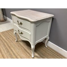 a white dresser sitting on top of a carpeted floor next to a gray wall