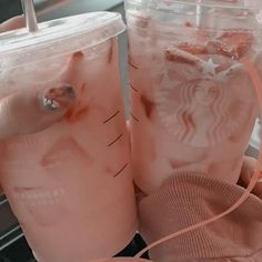 two starbucks iced drinks sitting on top of a counter next to a pink towel and bag