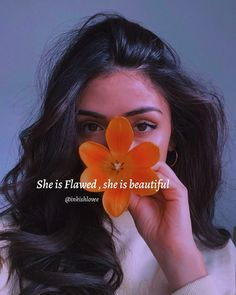 a woman holding an orange flower up to her face with the words she is loved, she is beautiful