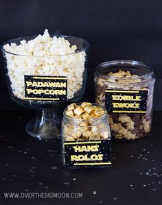 three glass containers filled with popcorn on top of a black tablecloth covered countertop