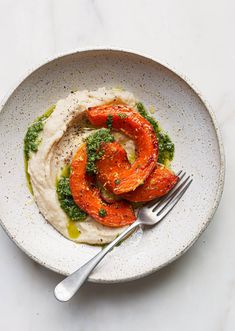 a white bowl filled with hummus, carrots and pesto