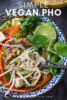 a blue and white bowl filled with noodles, carrots, celery, green onions and meat