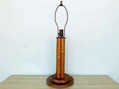 a wooden table with a lamp on top of it and a white wall in the background