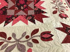 a close up of a quilt with red and pink flowers on it's edges