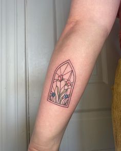 a woman's arm with a tattoo on it that has flowers in the window