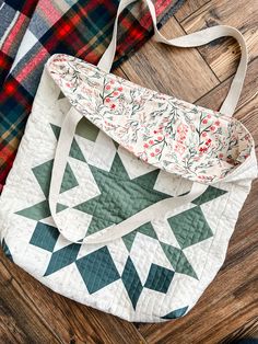 a quilted bag sitting on top of a wooden floor next to a plaid blanket