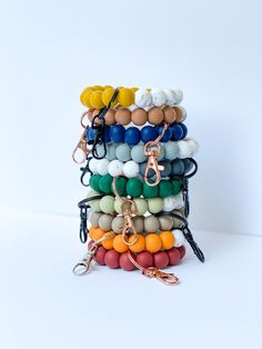 a stack of multicolored bracelets with metal clasps and key chains on white background