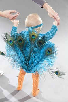 a baby dressed up like a peacock with feathers