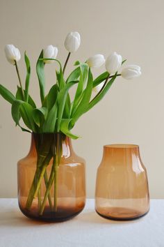 two vases with flowers in them sitting on a table