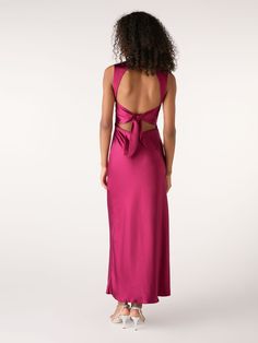 the back of a woman wearing a pink dress with a large bow on it's side