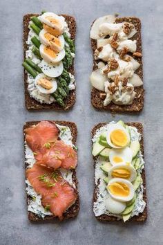 four slices of bread with eggs, asparagus and other food items on them