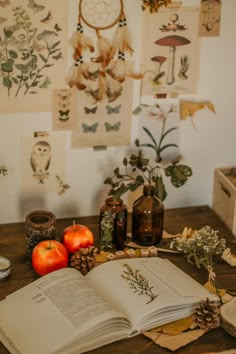 an open book sitting on top of a wooden table next to apples and other items