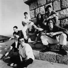 black and white photograph of men sitting on steps with one man leaning against the wall