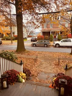 a house with fall leaves on the ground and cars parked in front of it,