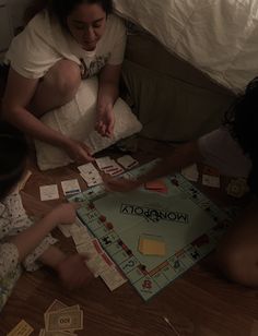 three people sitting on the floor playing monopoly