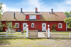 a red house with white picket fence in front of it