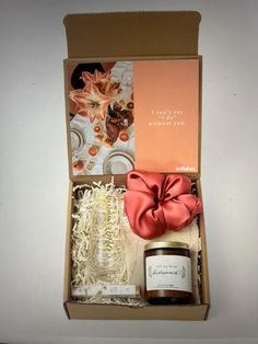 an open gift box containing a candle, jar and some other items that are in it