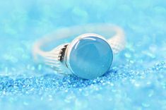 a blue ring sitting on top of a glittery surface with bubbles in the background