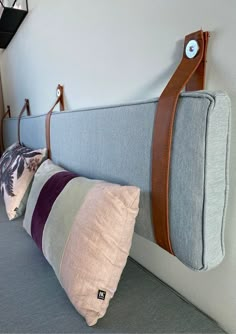 the headboard of a bed with two pillows on it and a leather strap hanging from the back