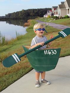 a young boy wearing sunglasses and holding a green boat shaped like a oarset