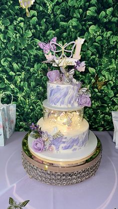 a three tiered cake sitting on top of a table next to a green wall