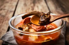 a bowl filled with stew and a wooden spoon in it on top of a napkin