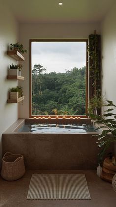 a bath tub sitting next to a window with a view of the forest outside it