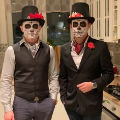 two men in skeleton makeup and top hats standing next to each other with roses on their foreheads