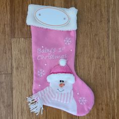 a baby's first christmas stocking with a snowman on it, sitting on a wooden floor