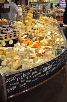 cheeses are displayed in a display case at a store