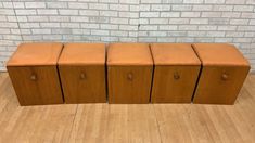 three wooden cabinets sitting on top of a hard wood floor next to a brick wall