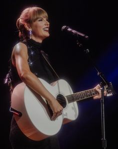 a woman singing into a microphone while holding a guitar