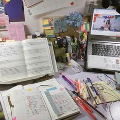 an open book sitting on top of a desk next to a laptop computer and other office supplies