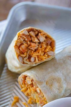 two burritos sitting on top of a metal tray