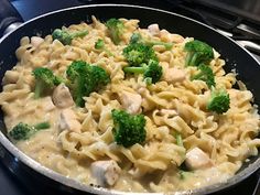 a skillet filled with pasta and broccoli on top of a stovetop