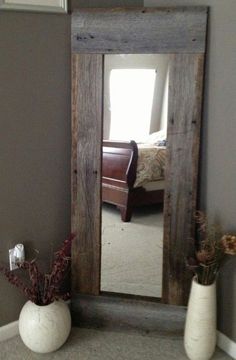 a mirror sitting on top of a floor next to two vases