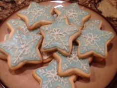 some blue and white decorated cookies on a plate with snowflakes in the middle