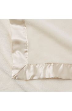 the white sheets are folded on top of each other, and there is a satin edge