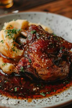 a white plate topped with meat and mashed potatoes