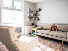 a living room with two couches and a book shelf on the wall next to a window